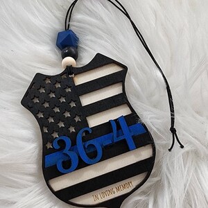 May include: Wooden ornament shaped like a police badge with an American flag design, blue "364" number, and "In Loving Memory" text.