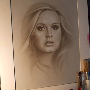 Puede incluir: Un dibujo a lápiz en blanco y negro de una mujer con cabello rubio. La mujer mira directamente al espectador con una expresión seria. El dibujo está enmarcado en un paspartú blanco.