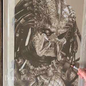 Könnte beinhalten: Eine detaillierte Bleistiftzeichnung des Predators, eines fiktiven außerirdischen Jägers aus dem Film-Franchise. Die Zeichnung ist in Grautönen und Braun gehalten und zeigt das Gesicht, den Kopf und den Oberkörper des Predators. Der Predator trägt einen Helm und hat eine Waffe auf dem Rücken befestigt. Die Zeichnung ist unten links mit "Barry Jones" signiert.
