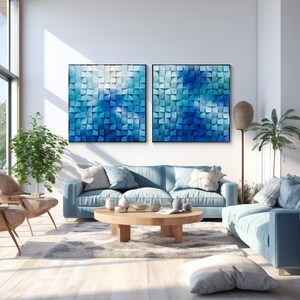 May include: Two blue abstract wall art pieces with a 3D geometric design. The pieces are made of wood and have a light blue, medium blue, and dark blue color scheme. The art is hanging on a white wall in a living room setting.