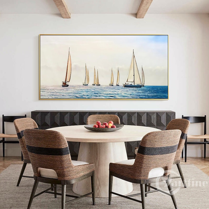 May include: A framed painting of a seascape with multiple sailboats on the water. The painting is in a gold frame and is hanging on a white wall above a wooden table with chairs.
