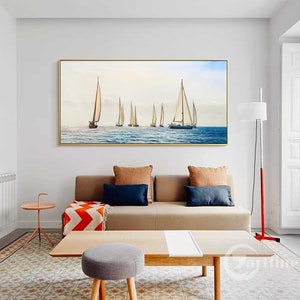 Pode incluir: Uma impress&atilde;o em tela emoldurada de uma paisagem mar&iacute;tima com veleiros em um mar azul calmo. A impress&atilde;o est&aacute; em um ambiente de sala de estar com um sof&aacute;, uma mesa de caf&eacute; e um abajur.