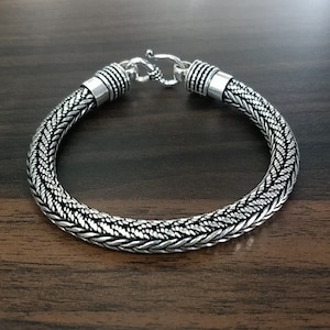 Puede incluir: Un brazalete de plata con un dise&ntilde;o trenzado. El brazalete tiene un cierre de broche.