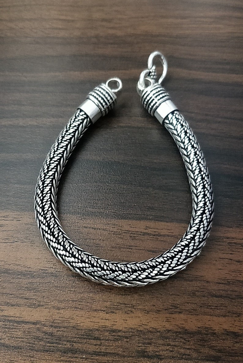 Puede incluir: Un brazalete de plata con un dise&ntilde;o trenzado. El brazalete tiene un cierre de broche.