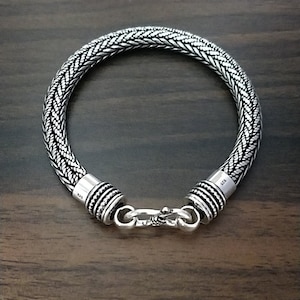 Puede incluir: Un brazalete de plata con un dise&ntilde;o trenzado y un cierre de broche.