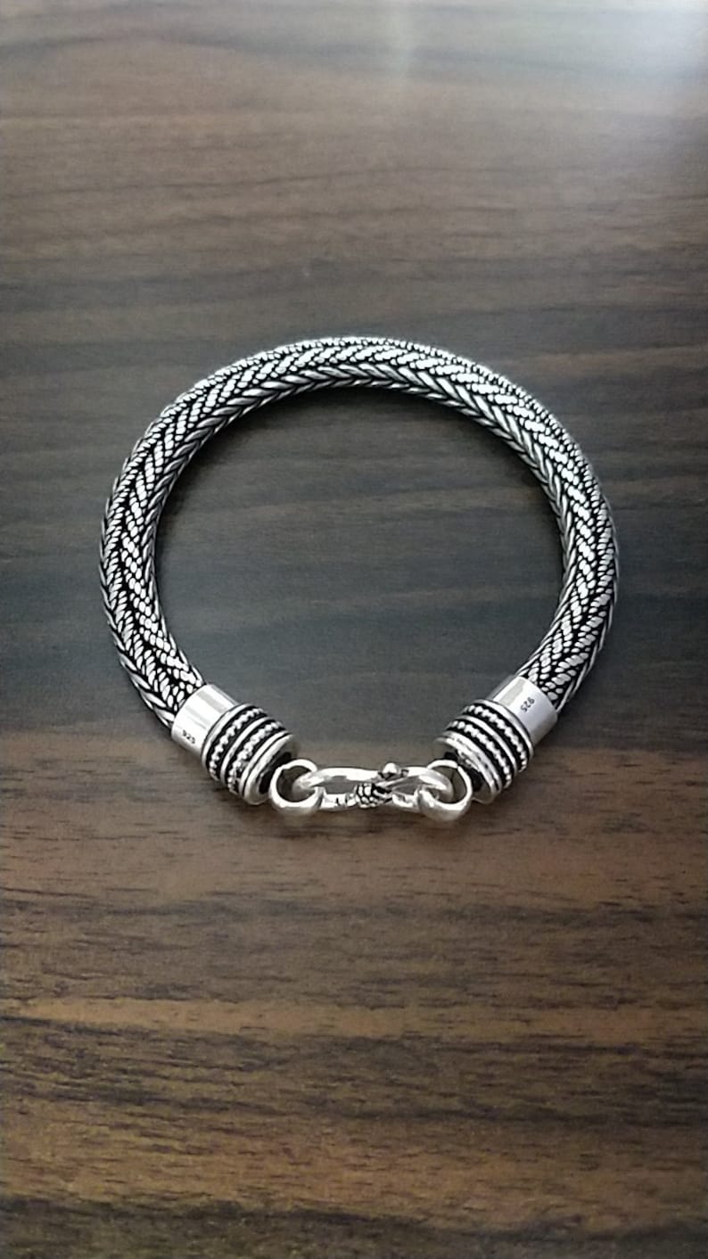 Puede incluir: Un brazalete de plata con un dise&ntilde;o trenzado y un cierre de broche.