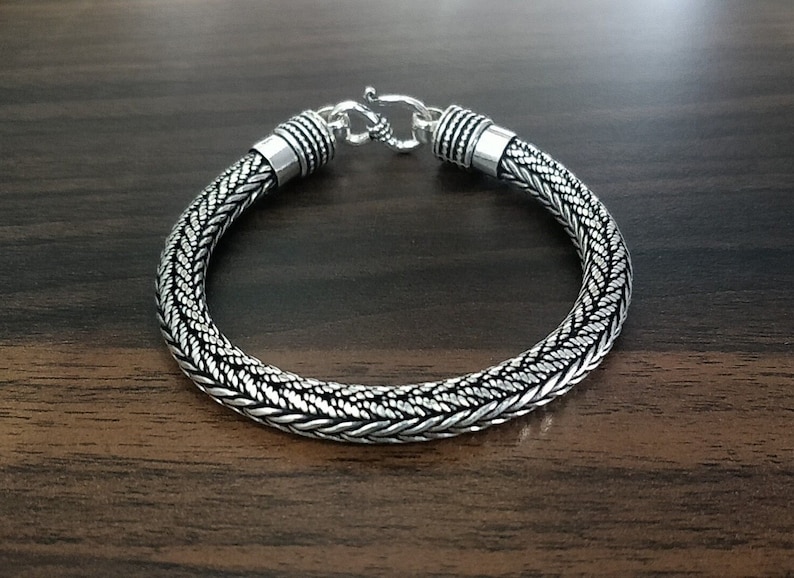 Puede incluir: Un brazalete de plata con un dise&ntilde;o trenzado. El brazalete tiene un cierre de broche.