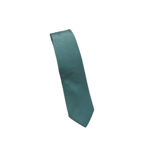 Peut inclure: Une cravate bleu sarcelle unie avec une finition lisse et satinée. La cravate présente une extrémité pointue en bas et une forme effilée qui s'élargit vers le haut. Le tissu a un éclat subtil qui reflète la lumière sur toute sa surface.