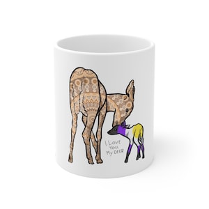 Puede incluir: Taza de cerámica blanca con una ilustración de una familia de ciervos. El ciervo adulto tiene un diseño estampado en tonos marrones y beige. El cervatillo está coloreado en morado, amarillo y blanco. El texto en la taza dice "I Love You, My DEER."