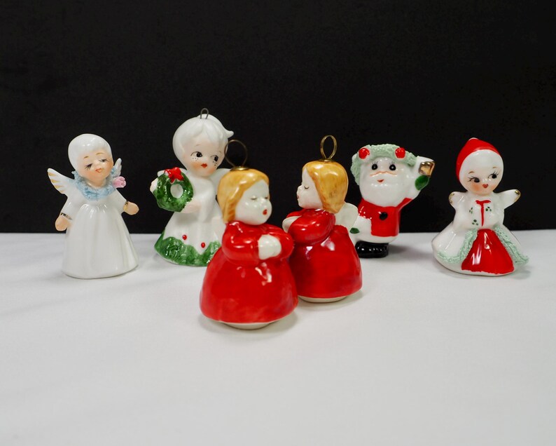 Puede incluir: Una colecci&oacute;n de adornos navide&ntilde;os vintage. Los adornos incluyen &aacute;ngeles, una figura de Pap&aacute; Noel y una ni&ntilde;a con un vestido rojo y blanco. Los adornos son de cer&aacute;mica y tienen detalles dorados. Los &aacute;ngeles tienen alas y vestidos blancos.