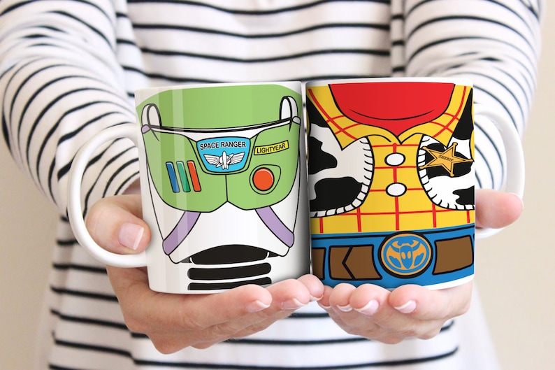 Puede incluir: Dos tazas de cer&aacute;mica blanca con dise&ntilde;os de personajes. Una taza presenta un dise&ntilde;o verde y blanco de Buzz Lightyear con las palabras "Space Ranger" y "Lightyear". La otra taza tiene un dise&ntilde;o de Woody con una camisa amarilla, pa&ntilde;uelo rojo y placa de sheriff.