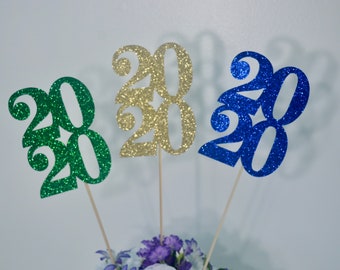 May include: Three 2020 graduation centerpieces in green, gold, and blue glitter.