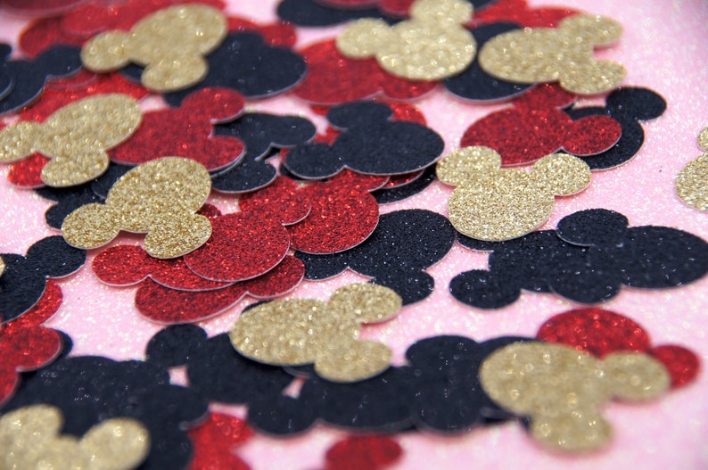 May include: A pile of red, black, and gold glitter Mickey Mouse head confetti.
