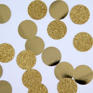 May include: Gold confetti circles scattered on a white background. Some circles have a shiny, reflective surface, while others are covered in gold glitter. The confetti is a festive decoration.