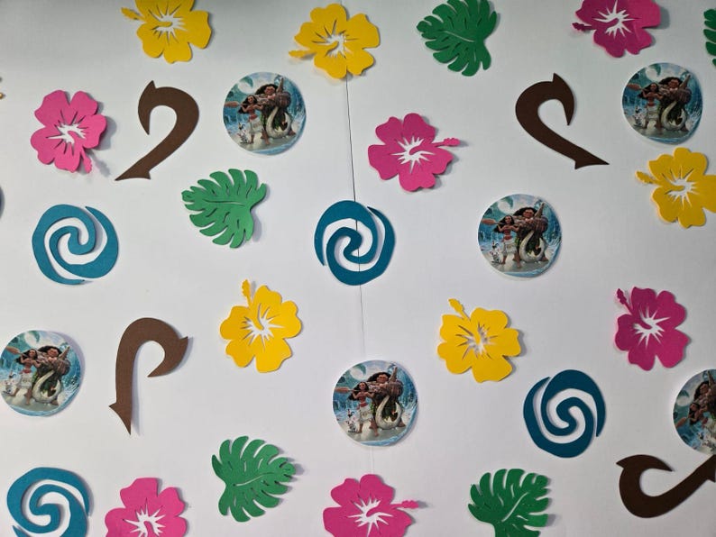 Pode incluir: Uma cole&ccedil;&atilde;o de decora&ccedil;&otilde;es para festas com tema Moana, incluindo recortes de papel de flores, folhas e o gancho do personagem Maui. H&aacute; tamb&eacute;m redemoinhos de papel azul e verde e recortes de papel redondos com imagens de Moana e Maui.