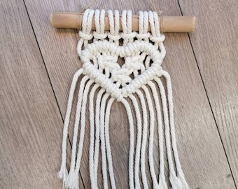 Petit cœur décoratif en macramé sur une branche de bois flotté