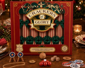 May include: A rectangular red box for the Crackers of Glory dinner table party game featuring striped crackers with green bows. Included are two miniature archery targets, a rubber band, a wooden ball, dice, and circular game tokens.