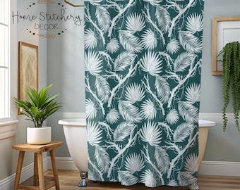 May include: Teal shower curtain with a white tropical leaf pattern. The shower curtain is hanging in a bathroom with a white bathtub and a green plant on a wooden stool.