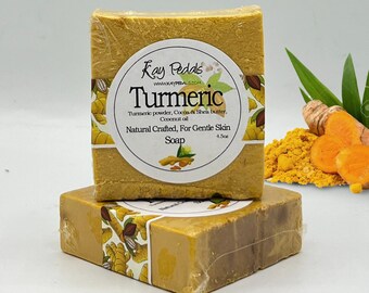 May include: Two bars of turmeric soap with a yellow label that reads "Kay Pedals" and "Turmeric" with ingredients listed. The label also says "Natural Crafted, For Gentle Skin" and "Soap".