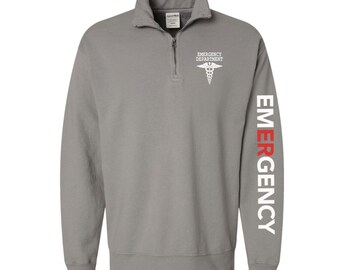 May include: Gray 1/4 zip sweatshirt with a white medical symbol and the text "Emergency Department" on the left chest. The right sleeve has the word "EMERGENCY" in white with the "E" in red.