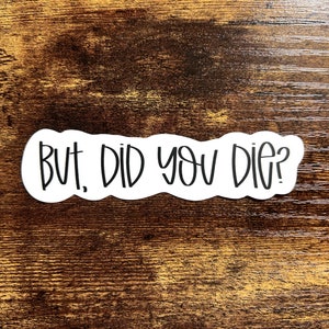 May include: White sticker with black text that reads "But, did you die?" on a brown wooden background.