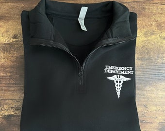 May include: Black 1/4 zip pullover sweatshirt with a white embroidered medical symbol and the text "Emergency Department".
