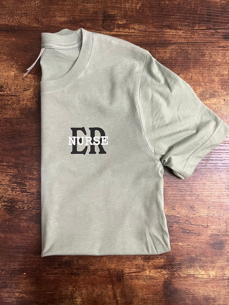 May include: A light green t-shirt with black text that reads "ER NURSE".