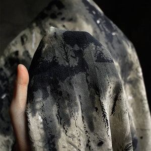 May include: A close-up of a piece of fabric with a black and white abstract print. The fabric is textured and has a soft, natural feel.