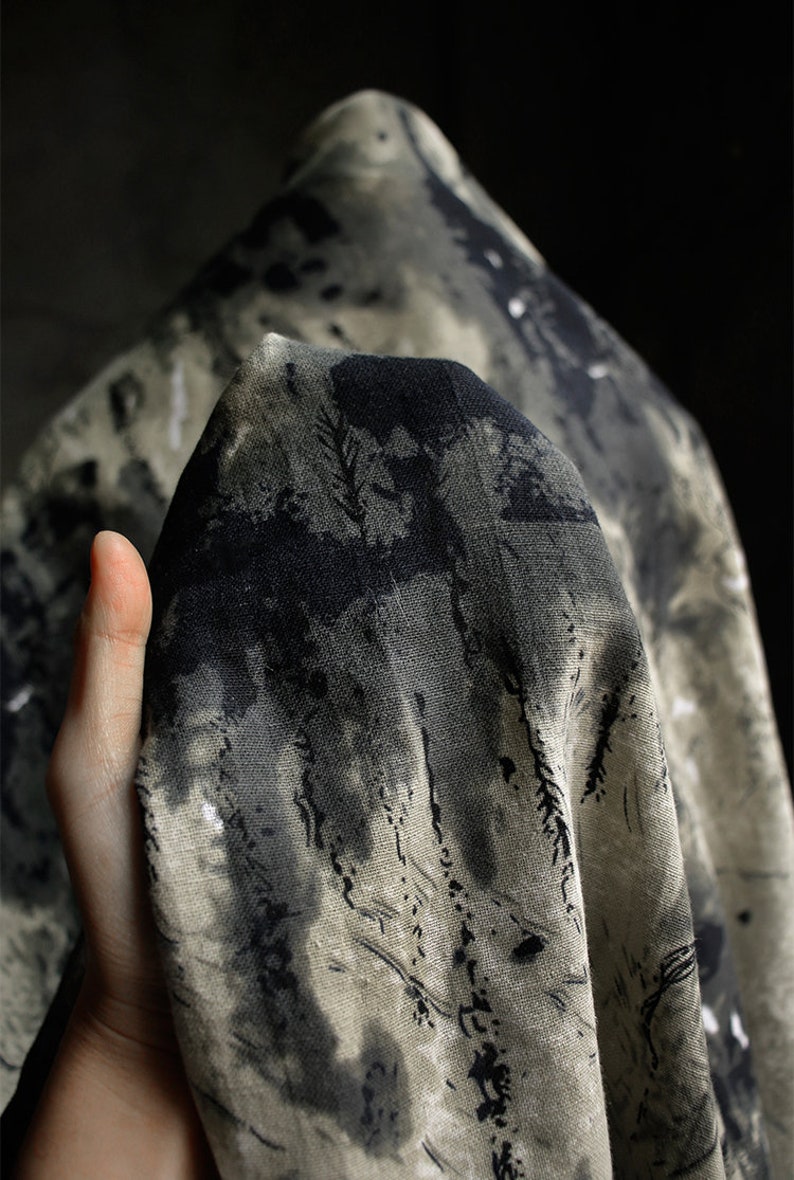 May include: A close-up of a piece of fabric with a black and white abstract print. The fabric is textured and has a soft, natural feel.
