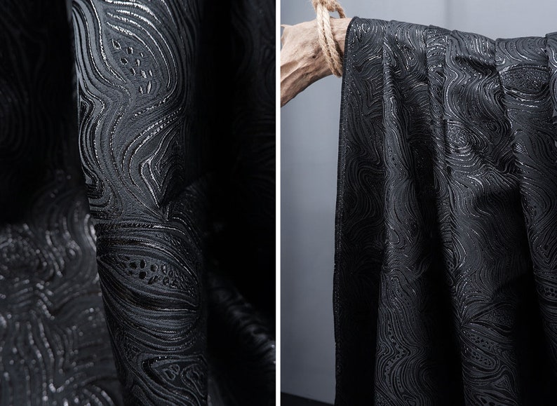 May include: Black fabric with a silver swirl pattern. The fabric is textured and has a subtle sheen.