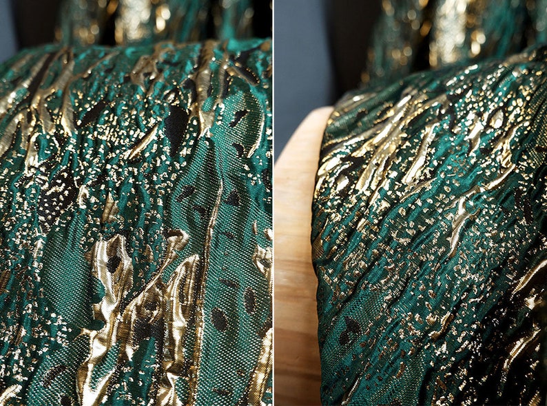 May include: Close-up of a green and gold fabric with a textured, embossed pattern. The fabric has a metallic sheen and a subtle shimmer.