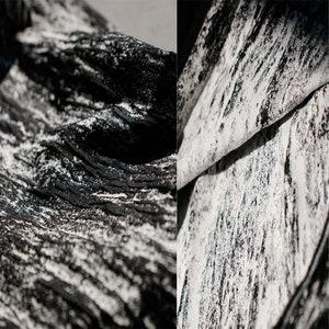May include: Close-up of a black and white fabric with a textured, brushstroke pattern. The fabric is folded over, revealing the white underside.