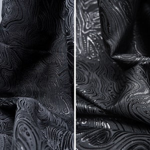 May include: Black fabric with a silver swirl pattern. The fabric is textured and has a subtle sheen.