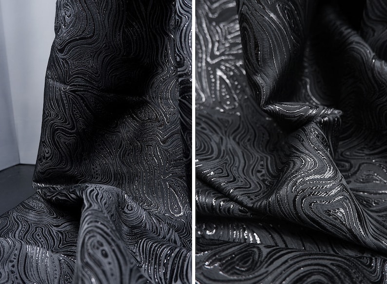 May include: Black fabric with a silver swirl pattern. The fabric is textured and has a subtle sheen.