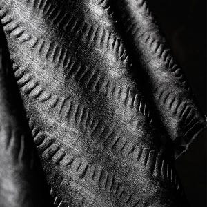 May include: Black fabric with a textured, chevron-like pattern. The fabric is soft and has a subtle sheen.