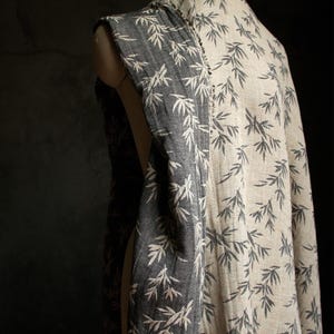 May include: A black and white fabric with a bamboo leaf pattern. The fabric is draped over a dress form.