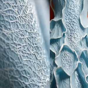 May include: Close-up of a light blue, textured fabric with a delicate, web-like pattern. The design features a series of interconnected lines, creating a lace-like appearance. The image showcases the intricate details and the subtle color variations of the material.