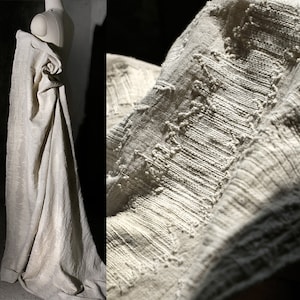Peut inclure: Un gros plan sur un tissu de lin blanc avec un motif tissé texturé. Le tissu est drapé sur une forme et a un aspect doux et naturel.