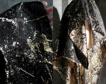 May include: Black fabric with gold metallic accents. The fabric has a textured, almost crinkled appearance. The gold accents are scattered across the fabric in a random pattern.