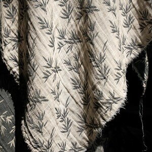 May include: A close-up of a piece of fabric with a black and white leaf pattern. The fabric is folded and has a frayed edge.