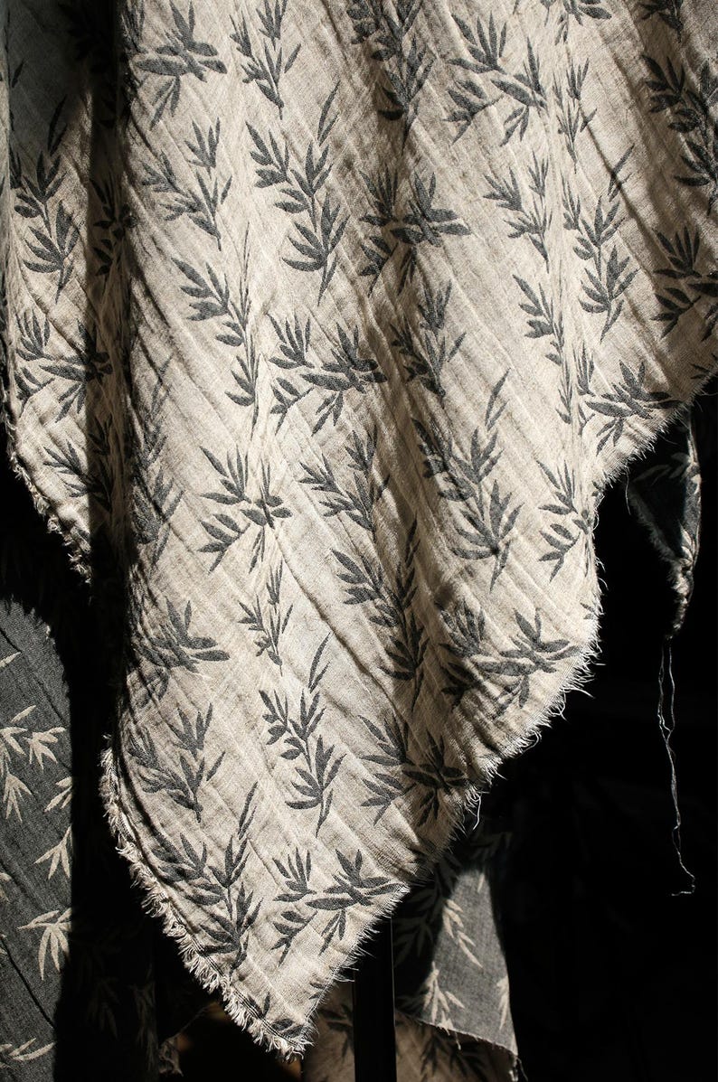 May include: A close-up of a piece of fabric with a black and white leaf pattern. The fabric is folded and has a frayed edge.