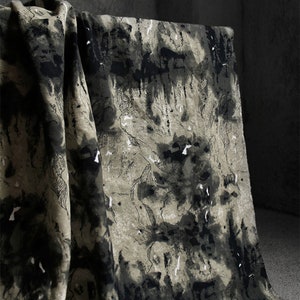 May include: Black and white abstract print fabric with a textured, linen-like feel. The fabric has a dark background with white and gray abstract shapes.