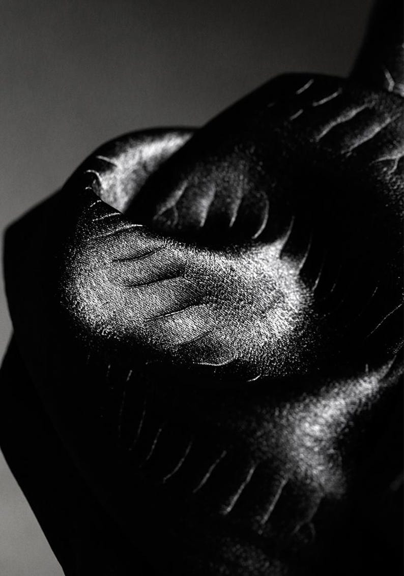 May include: Close-up of a black fabric with a subtle embossed pattern. The fabric has a smooth, silky texture and a slight sheen.