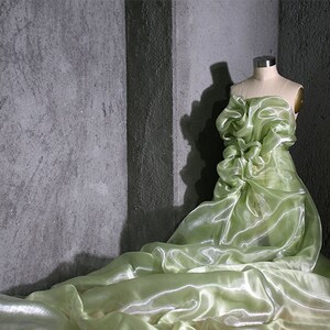 K&ouml;nnte beinhalten: Ein durchsichtiges, hellgr&uuml;nes Kleid mit einem R&uuml;schenoberteil, das auf einem Mannequin vor einem grauen Hintergrund pr&auml;sentiert wird.