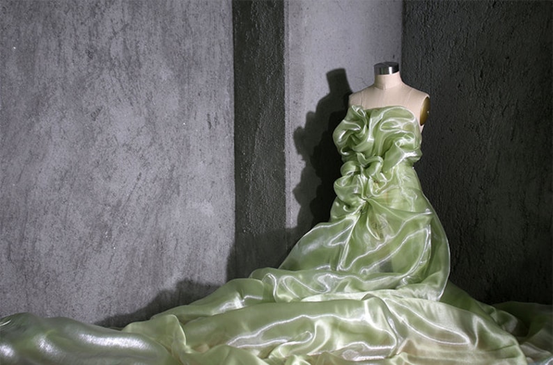 K&ouml;nnte beinhalten: Ein durchsichtiges, hellgr&uuml;nes Kleid mit einem R&uuml;schenoberteil, das auf einem Mannequin vor einem grauen Hintergrund pr&auml;sentiert wird.