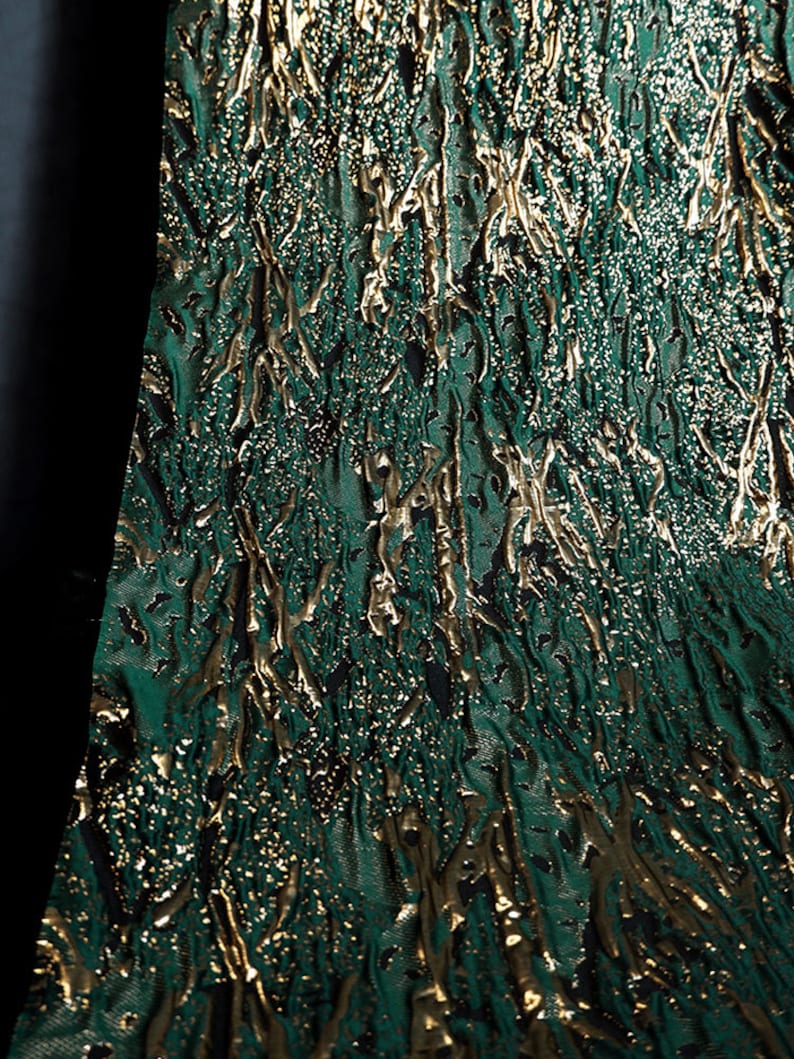 May include: Green fabric with a gold metallic pattern. The fabric has a textured, almost bark-like appearance.