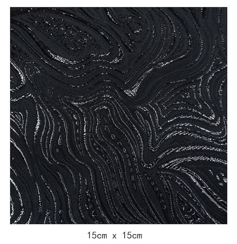 May include: Black fabric with a silver metallic swirl pattern. The fabric is 15cm by 15cm.