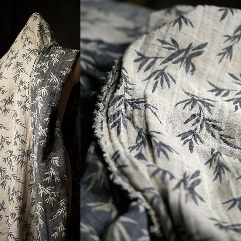 May include: A close-up of a beige fabric with a black bamboo leaf print. The fabric is folded and has a raw edge.