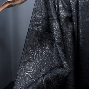 May include: Black fabric with a silver embossed pattern of swirling lines.
