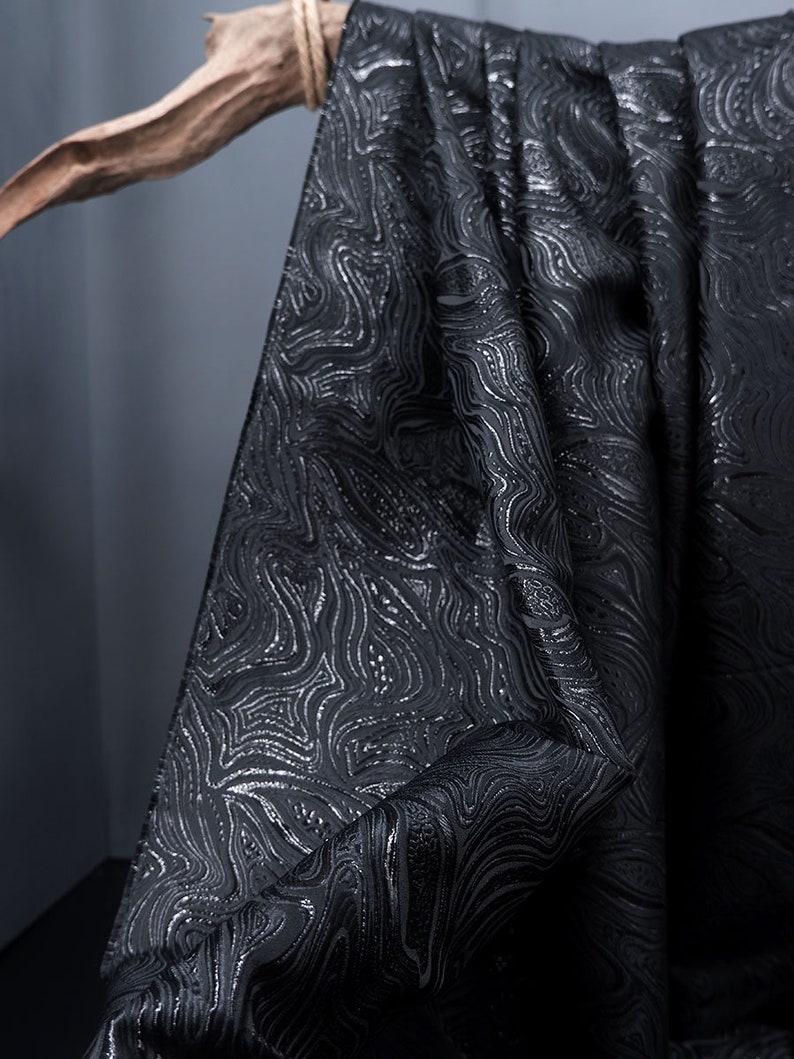 May include: Black fabric with a silver embossed pattern of swirling lines.